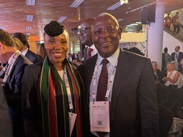Olivia Otieno in a Kenyan flag scarf posing with a delegate at an international conference