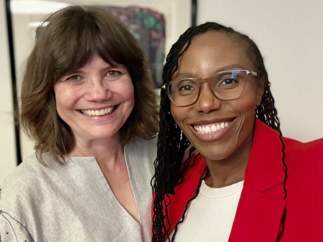Olivia Otieno in a red blazer smiling beside a colleague