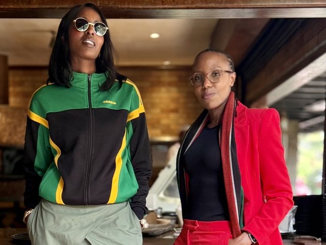 Olivia Otieno in a red suit standing beside a woman in a green and black jacket