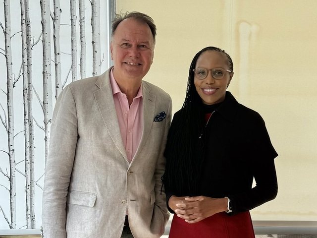 Olivia Otieno standing beside a man in a linen jacket by a large window