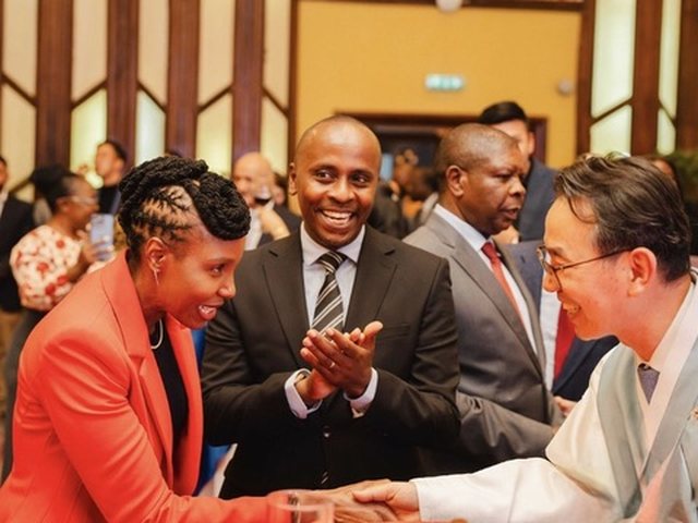 Olivia Otieno shaking hands with a guest at an event while others applaud