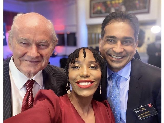 Olivia Otieno in a red dress taking a selfie with two guests at an evening event