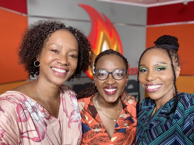 Olivia Otieno with two colleagues in front of the Spice FM flame logo in the radio studio