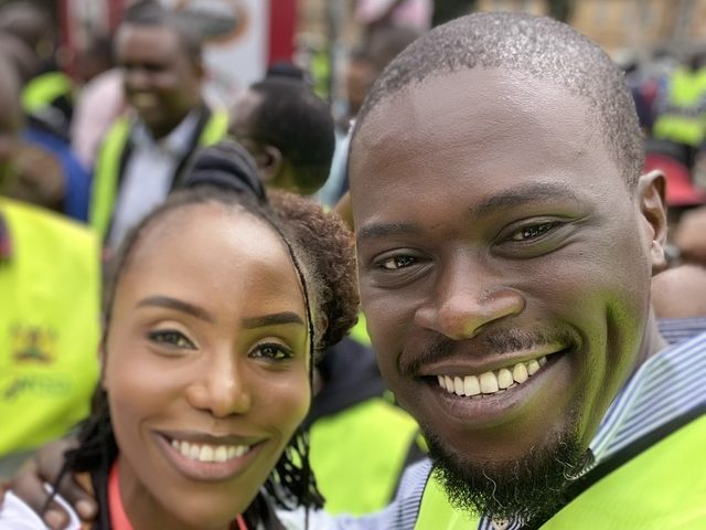 Olivia Otieno in a Jubilee Live Free Race jersey taking a selfie with a race marshal in a high-visibility vest