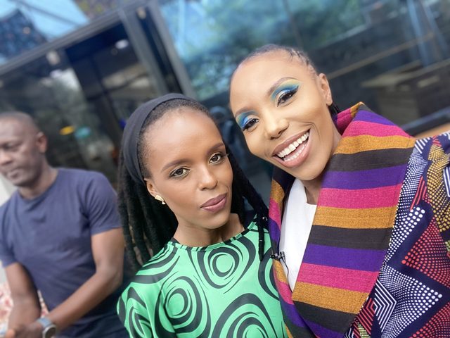 Olivia Otieno in a striped jacket taking a selfie with a colleague outside a glass building