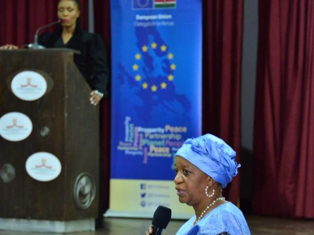 Olivia Otieno moderating at a podium while a guest speaks with a microphone at a European Union event