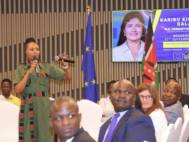 Olivia Otieno speaking with a microphone from the audience at a European Union event in Kisumu