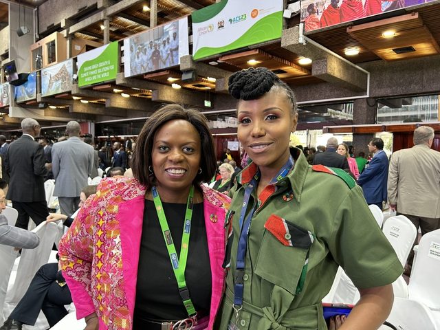 Olivia Otieno standing with a delegate in a pink jacket at the Africa Climate Summit