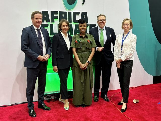 Olivia Otieno with four delegates in front of the Africa Climate Summit sign