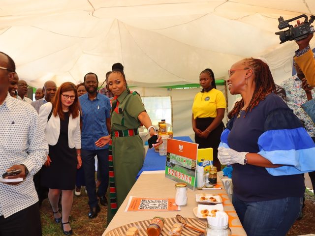 Olivia Otieno touring exhibition stalls with a group of guests under a tent